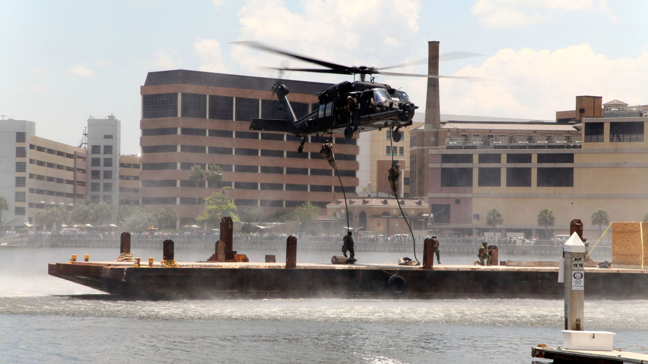 Multinational Special Operations Forces (SOF) fast-rope from a Blackhawk UH-60 helicopter onto a floating platform at a demonstration in Tampa, Florida as part of an international conference on Special Operations Forces in May 2014. 