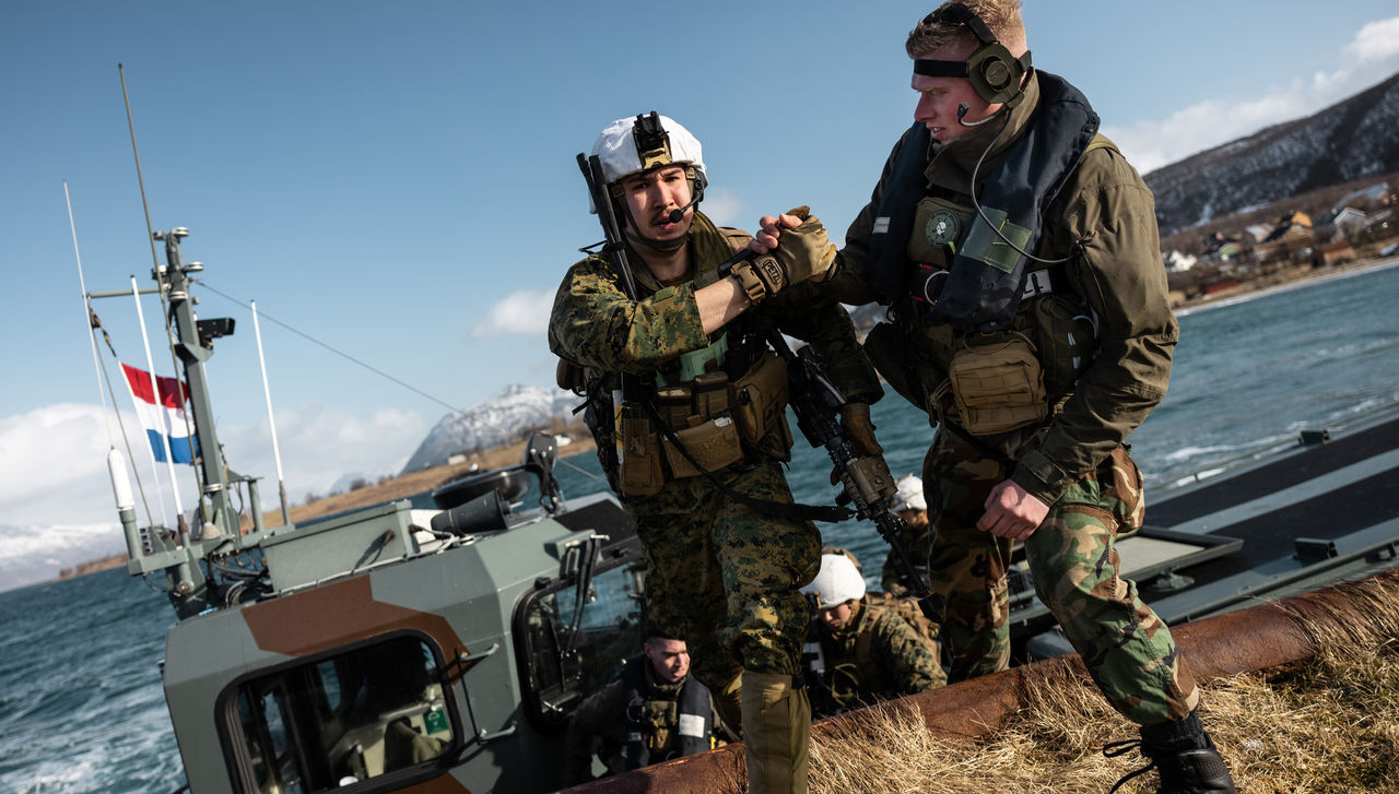 A Dutch amphibious reconnaissance marine helps a US marine off a Dutch landing craft near Sandstrand, Norway on 21 March during Exercise Cold Response 22.
