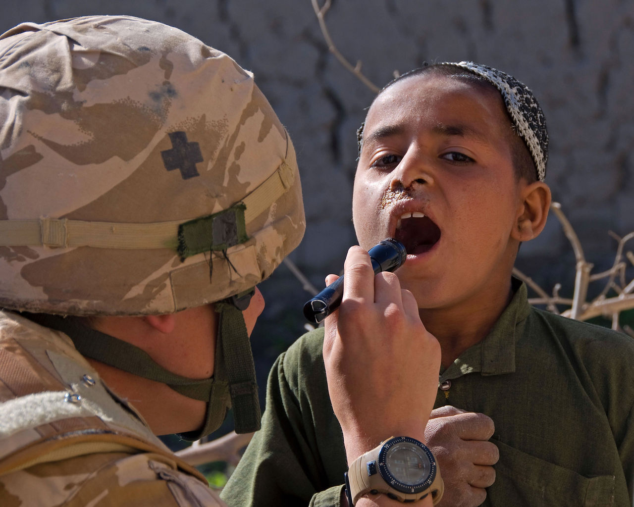 A medic from the Regimental Aid Post in the Sangin area of Helmand province examines a local boy.