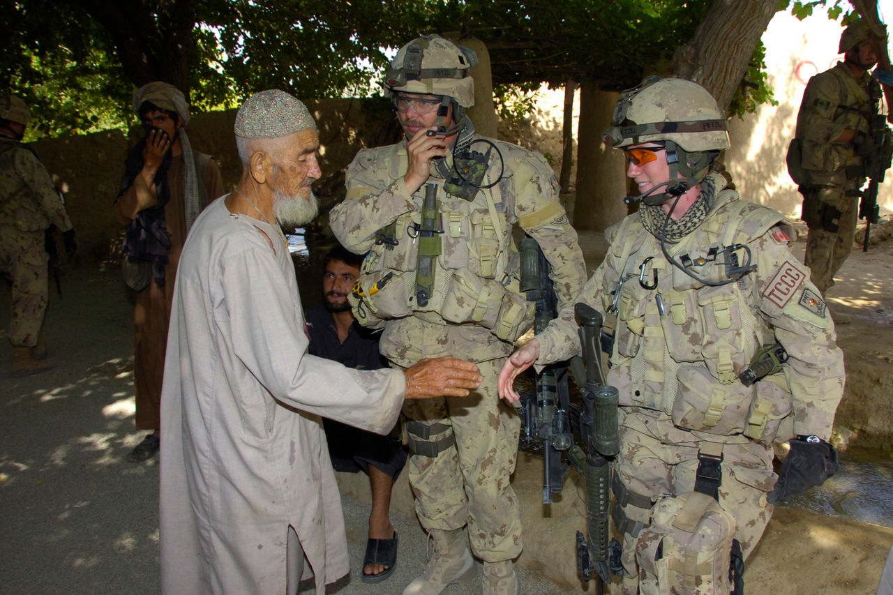 English/Anglais<br>
AR2007-B100-0069<br>
02 August 2007<br>
Kandahar Province, Afghanistan<br>
Photo by: Cpl Dan Pop<p>

Captain Kent MacRae and Warrant Officer Lori Coady of the Civil-Military Cooperation team (CIMIC) meet with a village elder to discuss ongoing projects. <p>

Working out of the Kandahar Provincial Reconstruction Team (KPRT) base in Camp Nathan Smith, the CIMIC team reaches out to Afghans to help provide a link between Afghans and their government.  This helps Afghans understand their government, how it works, and where they can go for aid and assistance.  CIMIC teams will also provide immediate assistance if there is a requirement.  This assistance could come in the form of projects to clear canals and allow water flow, digging of wells, or rehabilitation of buildings <p>

The KPRT consists of Canadian Forces members, a civilian police contingent led by the RCMP, Correctional Services Canada, representatives of the Department of Foreign Affairs and International Trade and the Canadian International Development Agency. The KPRT conducts coordinated interdepartmental operations to promote good governance, assists the Government of Afghanistan in extending its authority in the province of Kandahar, and facilitates the development of a stable, secure and self-sustaining environment for the people of Afghanistan. <p>

Joint Task Force Afghanistan (JTF-Afg) is Canada’s military contribution to Afghanistan. Canadian operations will focus on working with Afghan authorities to improve security, governance and economic development in the country. <p>

The Canadian Forces (CF) contribution in Afghanistan comprises over 2,500 soldiers, most of whom serve with JTF-Afg at Kandahar Airfield and Camp Nathan Smith, Canada’s Provincial Reconstruction Team (PRT), in Kandahar City.  Additional personnel are assigned to various military headquarters,  support bases, and civilian organizations.<p>

Photo by Corporal Dan Pop<br>
Kandahar Provincial Reconstruction Team Img Tech <p>