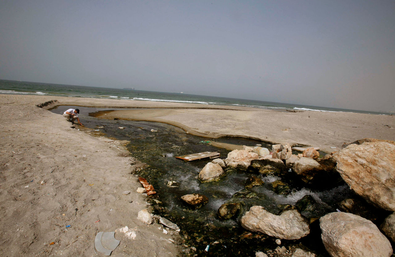 Ezer Fishler, from an environmental group called Zalul, kneels beside sewage flowing into the Mediterranean sea in the northern Israeli city of Haifa October 9, 2007. Heavy metals and pesticides are discharged into the sea under government licences, environmentalists say, and the company responsible for the sewage of the area's 2.5 million people is the biggest polluter in the eastern Mediterranean. The 21 countries ringing the Mediterranean share problems like coastal overdevelopment, overfishing and pollution but in Israel, long preoccupied with security issues, environmental awareness has been slow to take hold. Picture taken October 9, 2007.   To match feature ISRAEL-SEA/POLLUTION     REUTERS/Gil Cohen Magen (ISRAEL)