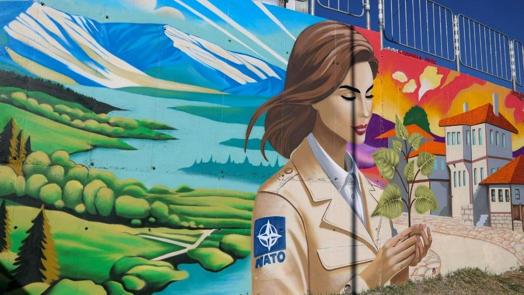 As part of Bulgaria’s celebrations for its 20th anniversary of NATO membership, the Ministry of Foreign Affairs organised a street art competition called “Bulgaria – More Beautiful in NATO”. On 7 November 2024, the first of five graffiti art murals was unveiled in Blagoevgrad. Created by graffiti studio The Graffs, the mural depicts a young soldier with a NATO badge on her shoulder.