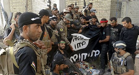 Żołnierze irackich sił bezpieczeństwa trzymają flagę Państwa Islamskiego, którą ściągnęli przy Uniwersytecie Anbar w prowincji Anbar 26 lipca 2015 roku. Irackie siły bezpieczeństwa wkroczyły na Uniwersytet Anbar w zachodnim mieście Al-Ramadi w niedzielę i starły się z bojownikami Państwa Islamskiego wewnątrz tego kompleksu, jak podało w oświadczeniu wspólne dowództwo operacji. © Reuters
)