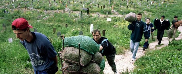 Sarajevans push and carry sacks of supplies as they across the main Sarajevo cemetary, July 7, 1995. © REUTERS
)