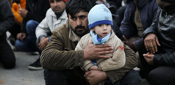 Un migrant afghan et son fils à leur arrivée dans un port de l'île grecque de Lesbos, après avoir été secourus en mer par la garde côtière grecque, en mars 2016. © REUTERS
)