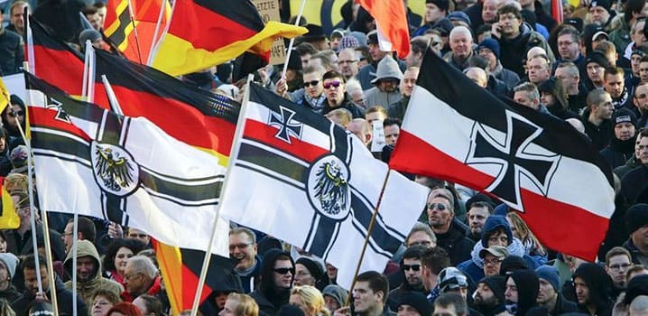 Des partisans du mouvement de droite anti-immigration PEGIDA (Européens patriotes contre l'islamisation de l'Occident) arborent diverses versions du drapeau de guerre impérial lors d'une marche organisée à Cologne (Allemagne) en janvier 2016. © Reuters
)