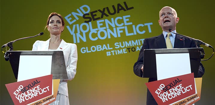 Actress and Special Envoy of the UN High Commissioner for Refugees, Angelina Jolie, and the then British Foreign Secretary William Hague speak at a global summit to end sexual violence in conflict, in London (10 June 2014). © REUTERS
)