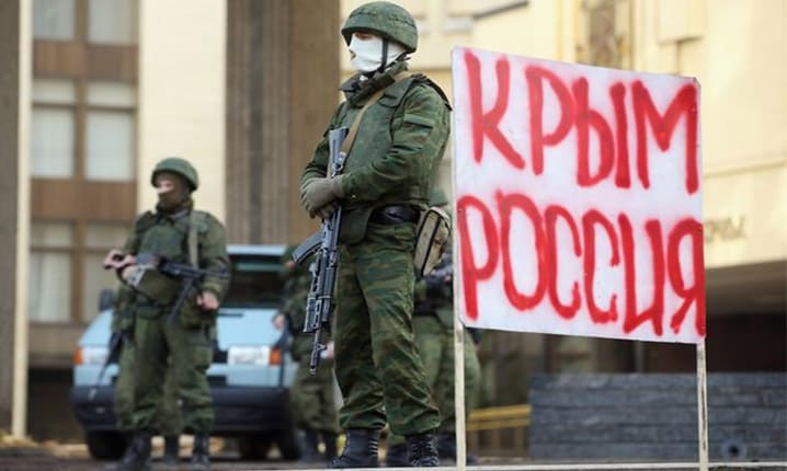 Des soldats sans insignes – les « petits hommes verts » – montent la garde devant le Parlement de la Crimée, à côté d'un panneau sur lequel on peut lire « La Crimée est russe » (2 mars 2014).
