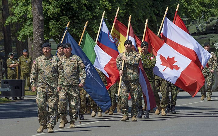  Альянс переорієнтовує увагу на свою основну місію колективної оборони. Зображені на фото прапороносці, що представляють Албанію, Канаду, Італію, Латвію, Польщу, Словенію і Іспанію відзначають створення своєї нової бойової групи в Латвії 19 червня 2017 року. Вона є частиною посиленої передової присутності НАТО  стримувати Росію, яка відроджує свою агресивність. Фото: Капрал Колін Томсон, фототехнік, ООТГ – Європа.
