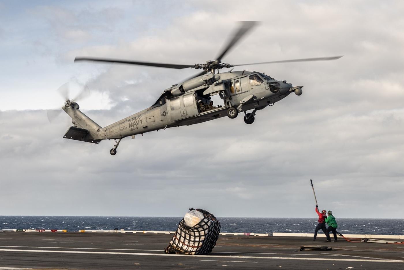 An H-60 Sierra utility helicopter performs a “VertRep” (vertical replenishment), where helicopters yo-yo between the Ford’s flight deck and an adjacent supply ship, slinging crates of supplies beneath them.
)