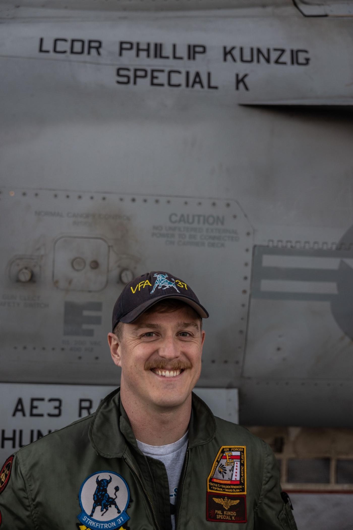 Lieutenant Commander Phillip Kunzig poses next to his F/A-18E Super Hornet on the deck of the USS Gerald R. Ford.
)