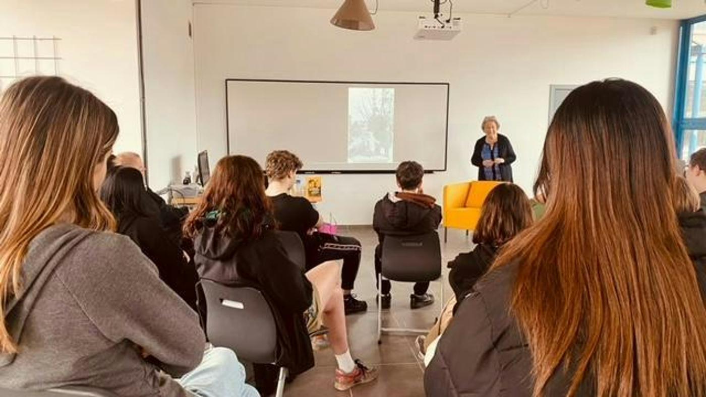 Baroness Regina Sluszny explains her story in pictures to teenagers in a school in Antwerp, 2022.
)