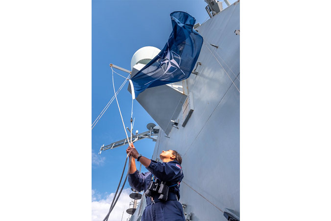 A sailor on the UK Royal Navy's HMS Diamond raises the NATO flag as the ship joins NATO Allies and partners as part of Standing NATO Maritime Group Two (SNMG2) in the Mediterranean Sea. Photo by UK Royal Navy. 