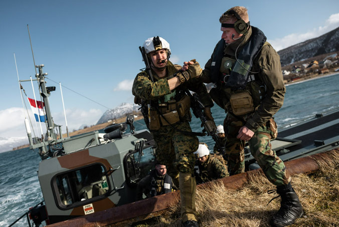 A Dutch amphibious reconnaissance marine helps a US marine off a Dutch landing craft near Sandstrand, Norway during exercise Cold Response 22, a Norwegian-led multinational exercise that helps NATO Allies train for military operations in the High North. Dutch, French and US forces were part of the more than 30,000 troops from 27 NATO member and partner countries to test their mettle against the harsh, demanding terrain of the Norwegian Arctic. Photo by NATO photographer.