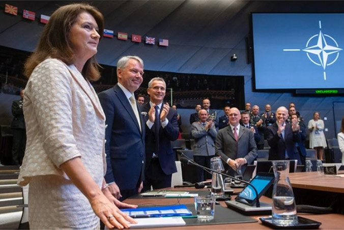 NATO Secretary General Jens Stoltenberg (third from left) and Allied Ambassadors to the North Atlantic Council applaud after signing the Accession Protocols for Finland and Sweden at NATO Headquarters in Brussels, in the presence of Finnish Foreign Minister Pekka Haavisto and Swedish Foreign Minister Ann Linde. The signature of the Accession Protocols marked the start of the ratification process, after which Finland and Sweden will be full NATO members. Photo by NATO photographer.