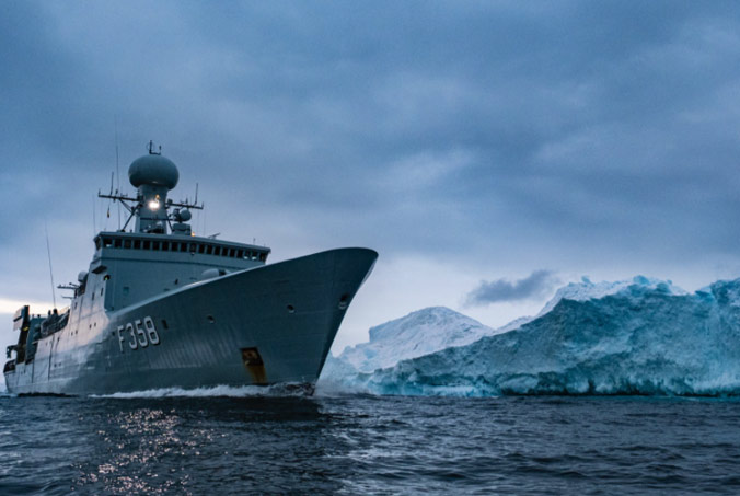 The Royal Danish Navy ship HDMS Triton sails next to an iceberg while on patrol off the coast of Greenland. Photo by NATO photographer.