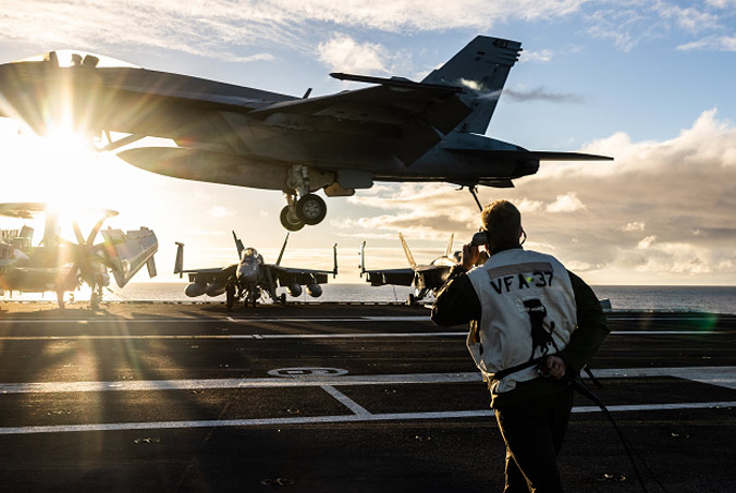 A US Navy Lieutenant Commander watches as an F/A-18E Super Hornet strike fighter lands on the flight deck of the USS Gerald R. Ford during exercise Silent Wolverine, a series of maritime drills off the coast of Portugal, which involved 11 ships from seven NATO countries. Photo by NATO photographer.