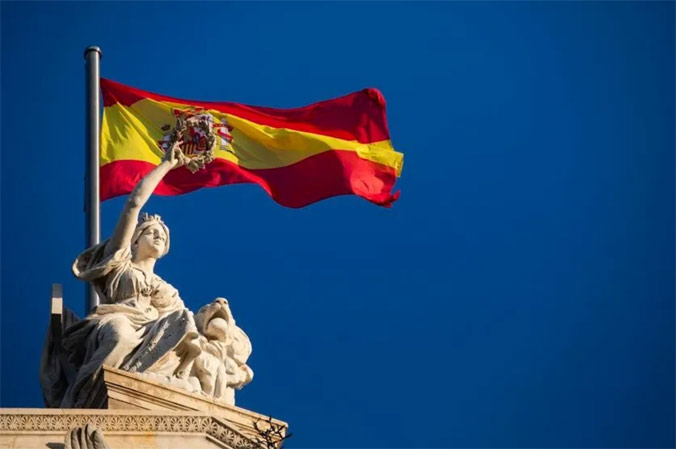 Hispania, the national personification of Spain, holds aloft a laurel wreath in front of the Spanish flag. The statue sits atop the National Library of Spain in Madrid. (Photo credit: Jesus G. Feria/La Razon)