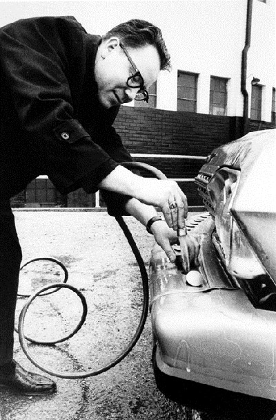 A man pipetting non-petroleum fuel into one of the low-polluting display vehicles