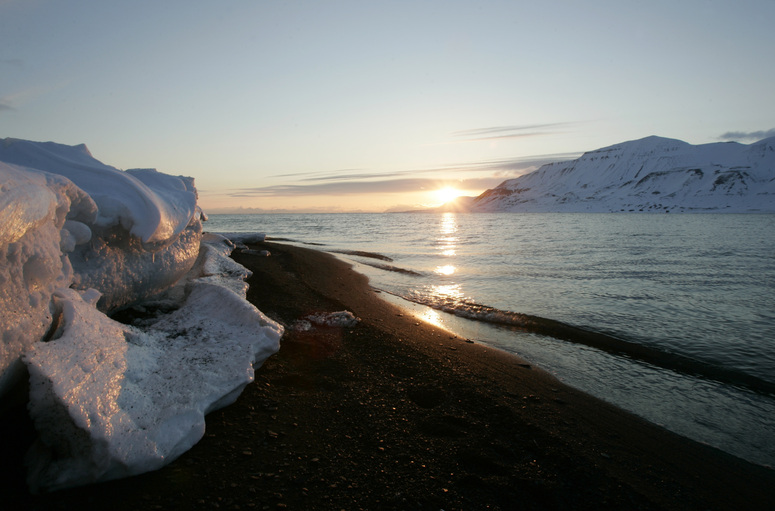 The sun shines low in the sky just after midnight over a frozen coastline near the Norwegian Arctic town of Longyearbyen, April 26, 2007. The sea water is normally frozen solid at this time of year but global warming may be warming the region.      REUTERS/Francois Lenoir   (NORWAY)